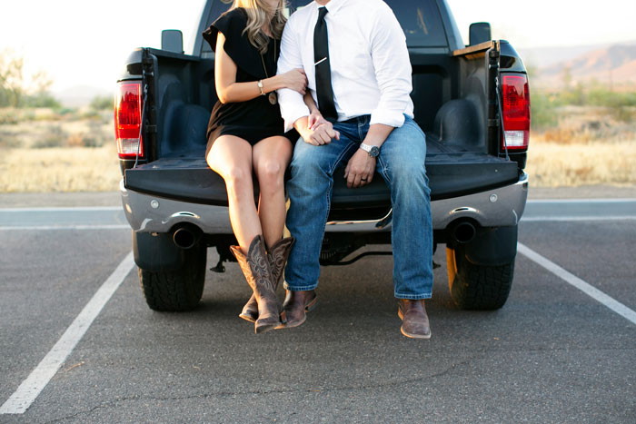 Couple sitting on truck bed holding hands illustrating coworker embarrassment at work Couple sitting on truck bed holding hands illustrating coworker embarrassment at work