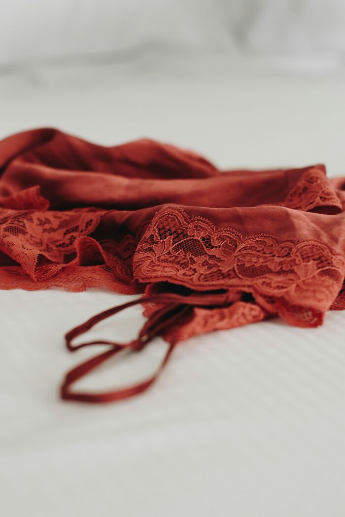 A red lace slip and matching top laying on a white bed, representing a romantic turn off for some men.