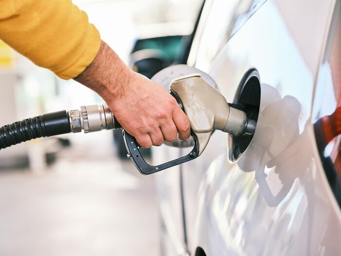 Hand refueling car with gasoline at gas station