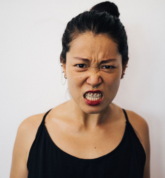 A woman with a parenting fail expresses extreme anger, showing her teeth, eyes squinted, with a nose ring. A woman with a parenting fail expresses extreme anger, showing her teeth, eyes squinted, with a nose ring.