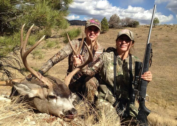 Hunters posing with a deer and firearms outdoors Hunters posing with a deer and firearms outdoors