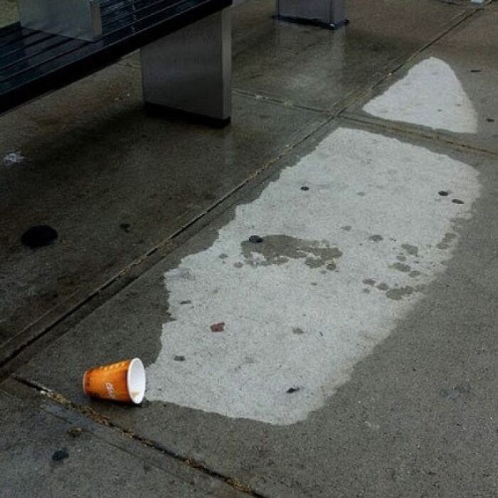 Spilled coffee creating wet stain resembling a footstep on concrete floor