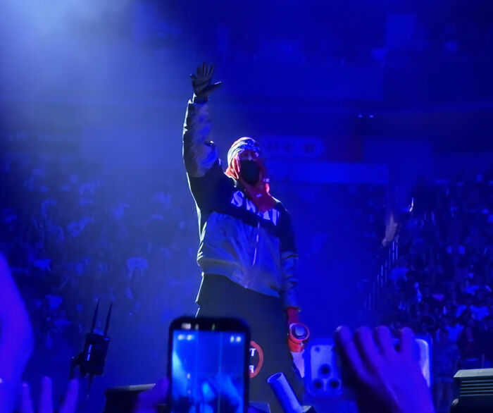 Rihanna's partner on stage, hands raised, after being accused of disrespecting Rihanna with a racy comment.