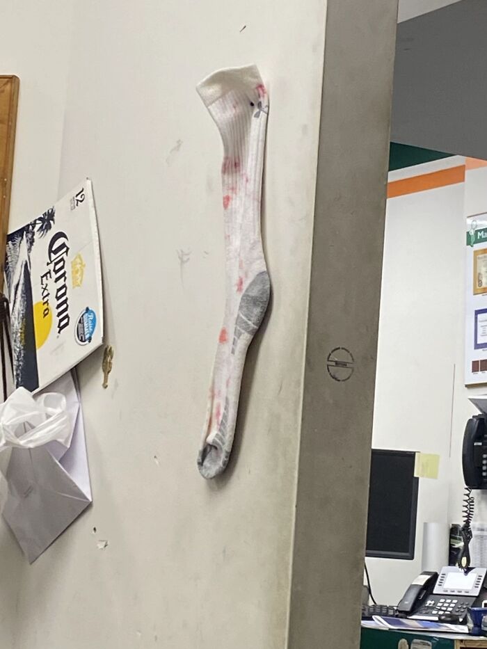 A bizarre white sock with red markings stuck vertically to a wall, possibly a refrigerator door.