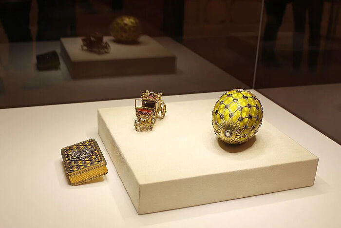 An exquisite collection of three lost treasures including a golden egg, a tiny carriage, and a jeweled box.