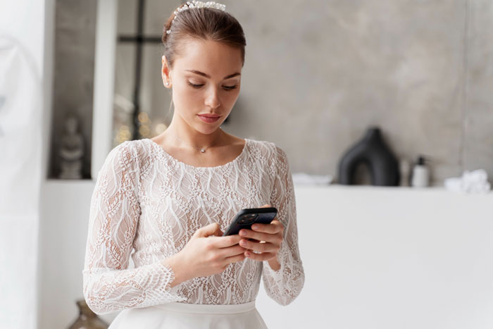 Bride in lace gown looking at phone, reflecting wedding drama Bride in lace gown looking at phone, reflecting wedding drama