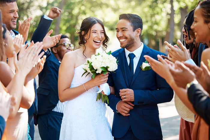 Happy bride and groom smiling at wedding surrounded by applauding guests Happy bride and groom smiling at wedding surrounded by applauding guests