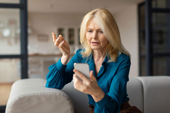 Frustrated woman looking at phone in discussion about wedding drama Frustrated woman looking at phone in discussion about wedding drama