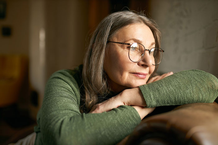 Elderly woman in green sweater looking thoughtfully out window Elderly woman in green sweater looking thoughtfully out window