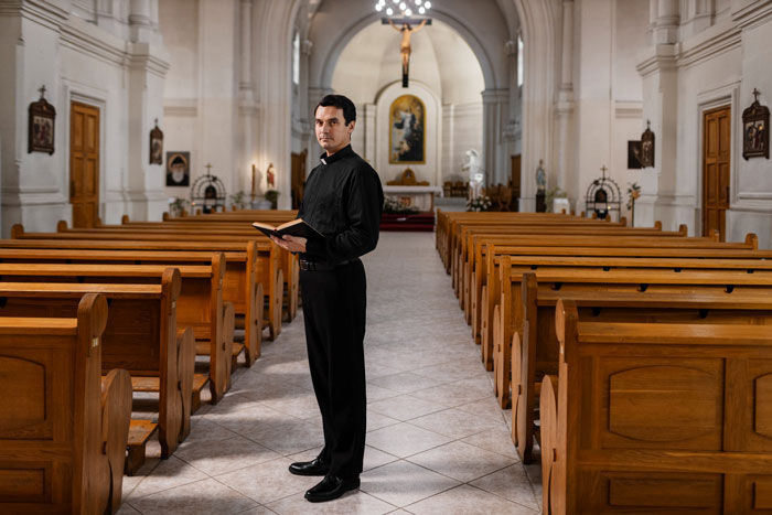 Pastor standing in a church aisle holding a book during a service Pastor standing in a church aisle holding a book during a service