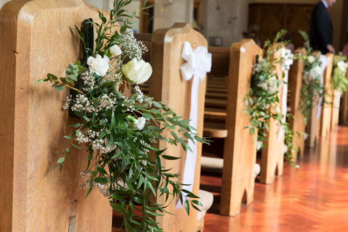 Church pews decorated with flowers and ribbons for wedding Church pews decorated with flowers and ribbons for wedding