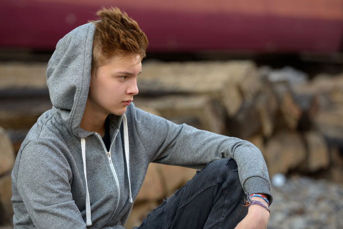 Teen boy sitting alone, reflecting on family and half siblings situation Teen boy sitting alone, reflecting on family and half siblings situation