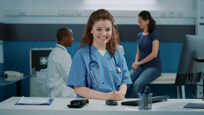 Smiling nurse at desk with doctor and patient in medical clinic setting Smiling nurse at desk with doctor and patient in medical clinic setting