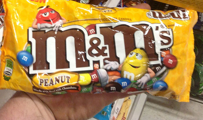 Hand holding peanut M&Ms candy pack showing popular snack choice