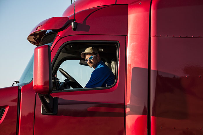 Truck driver in red semi truck cabin representing unwritten rules between strangers