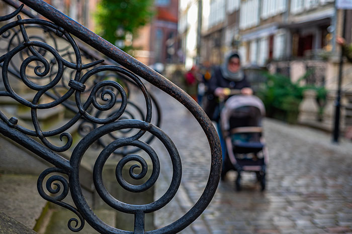 Decorative iron railing with blurred stroller in city street scene