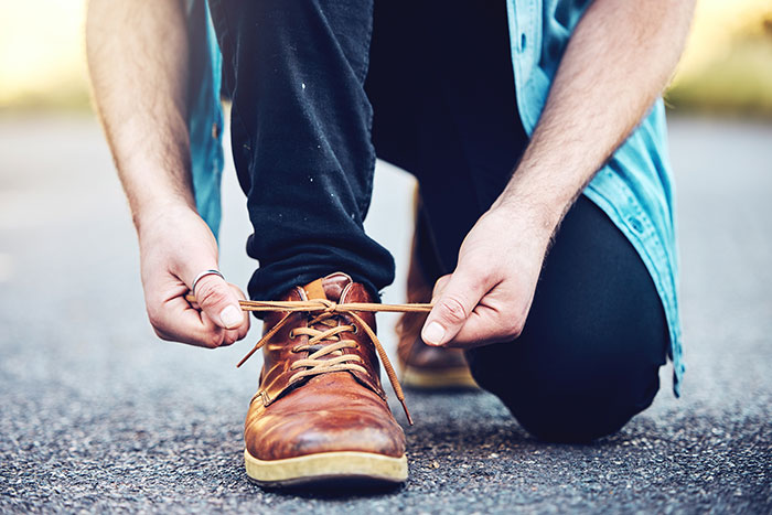 Man tying brown boots, illustrating unwritten rules between strangers