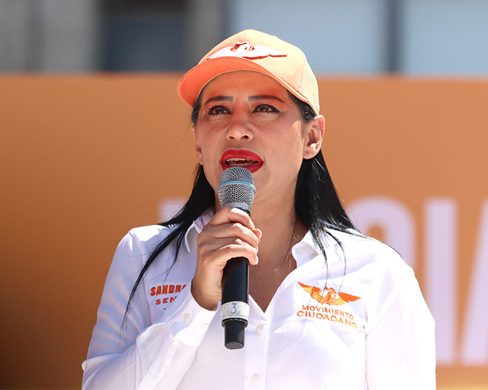 Former mayor speaking into a microphone, wearing a white shirt and orange hat, addressing the world cup outfit uproar. Former mayor speaking into a microphone, wearing a white shirt and orange hat, addressing the world cup outfit uproar.