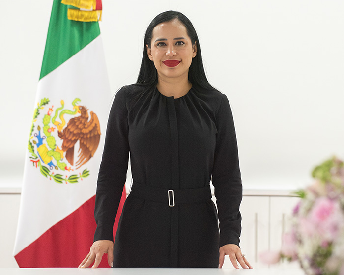 Former mayor in a professional setting, standing in front of a Mexican flag, after World Cup outfit uproar. Former mayor in a professional setting, standing in front of a Mexican flag, after World Cup outfit uproar.