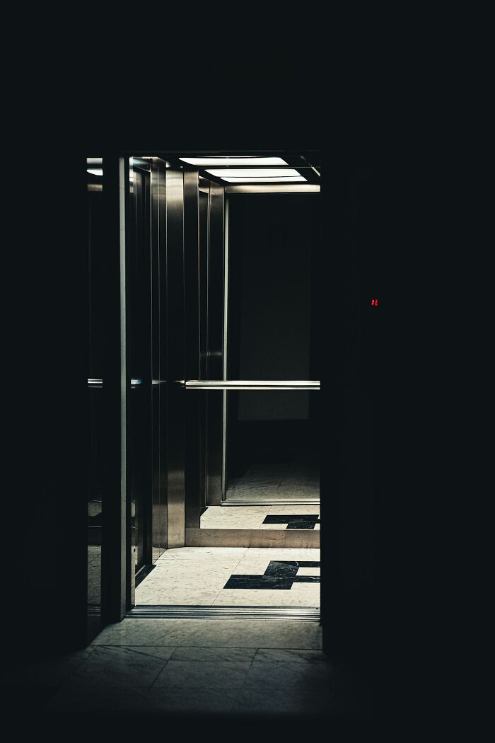 An empty, dark elevator with its doors open, symbolizing unexplainable experiences people can't explain.