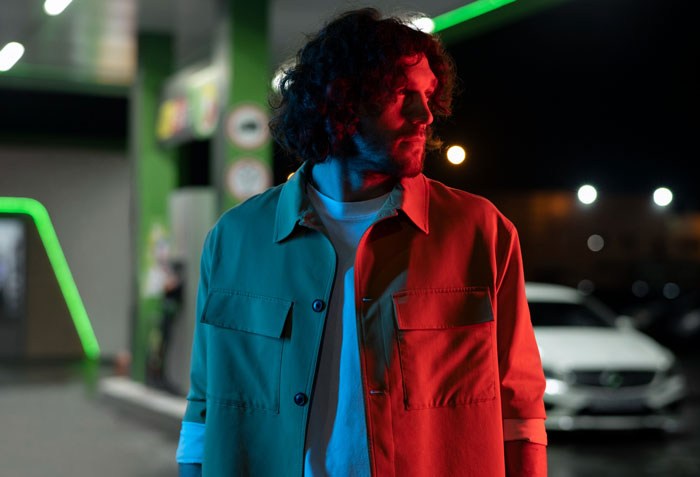 Man looking away in parking lot under colorful lights at night Man looking away in parking lot under colorful lights at night