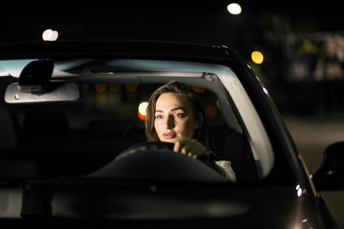 Woman driving car looks cautiously at the road at night Woman driving car looks cautiously at the road at night