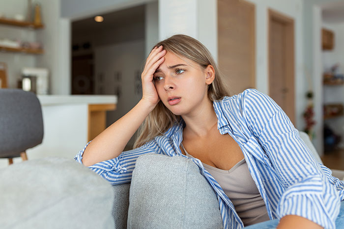 Worried woman sitting on couch stressed about wedding decisions Worried woman sitting on couch stressed about wedding decisions