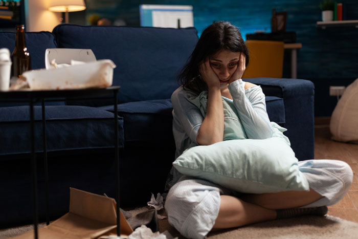 A sad woman with a pillow, sitting on the floor after a selfish friend incident with her blind date. A sad woman with a pillow, sitting on the floor after a selfish friend incident with her blind date.