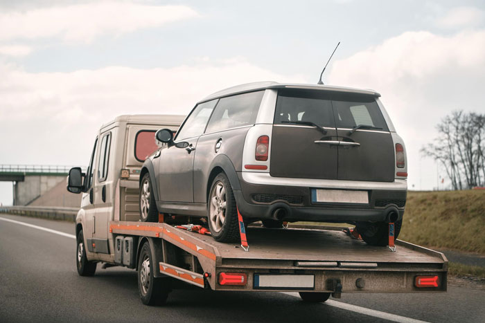 A car is being towed on a highway, illustrating the woman's car towed by a selfish friend. A car is being towed on a highway, illustrating the woman's car towed by a selfish friend.
