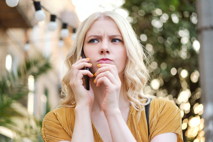 A confused woman on the phone, facing petty payback from a selfish friend. A confused woman on the phone, facing petty payback from a selfish friend.