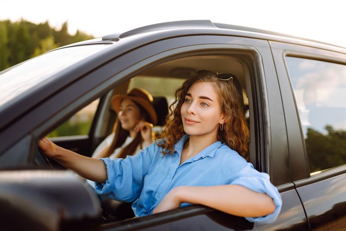 A woman driving a car, a selfish friend sitting next to her. The main character is about to face petty payback. A woman driving a car, a selfish friend sitting next to her. The main character is about to face petty payback.