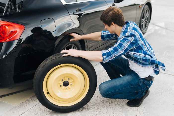 Man changing car tire representing generous acts and helpful moments