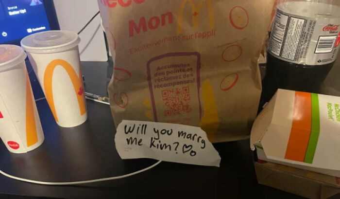 A Mcdonald's meal with a handwritten note that says Will you marry me Kim?, next to food, a humorous delivery fail.