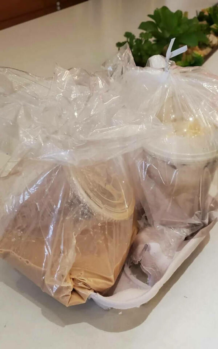 A plastic bag containing spilled food and drinks on a table, representing significant delivery fails.