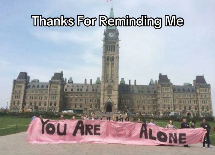 People holding a pink banner in front of a building that says YOU ARE ALONE, an example of bad design fails.