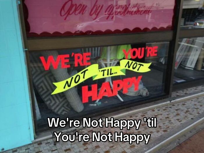 A hilariously bad design fail with a store sign that reads 'We're Not Happy 'til You're Not Happy', displaying poor grammar.