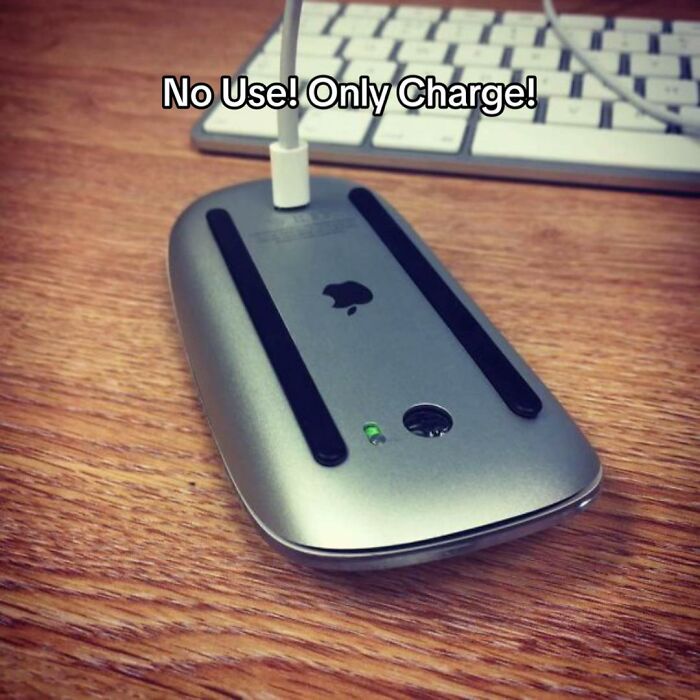 A hilariously bad design fail shows an Apple Magic Mouse being charged from underneath, making it unusable.