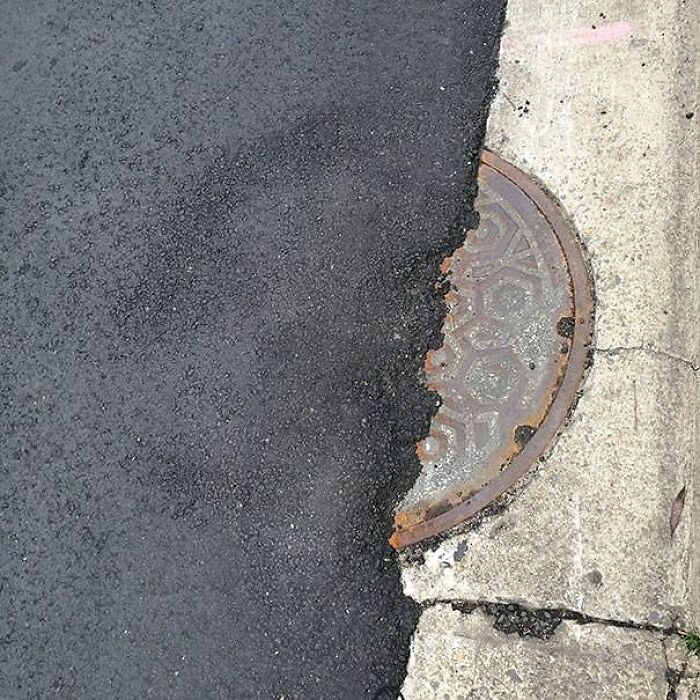 Cringeworthy design fail with asphalt covering half a manhole cover