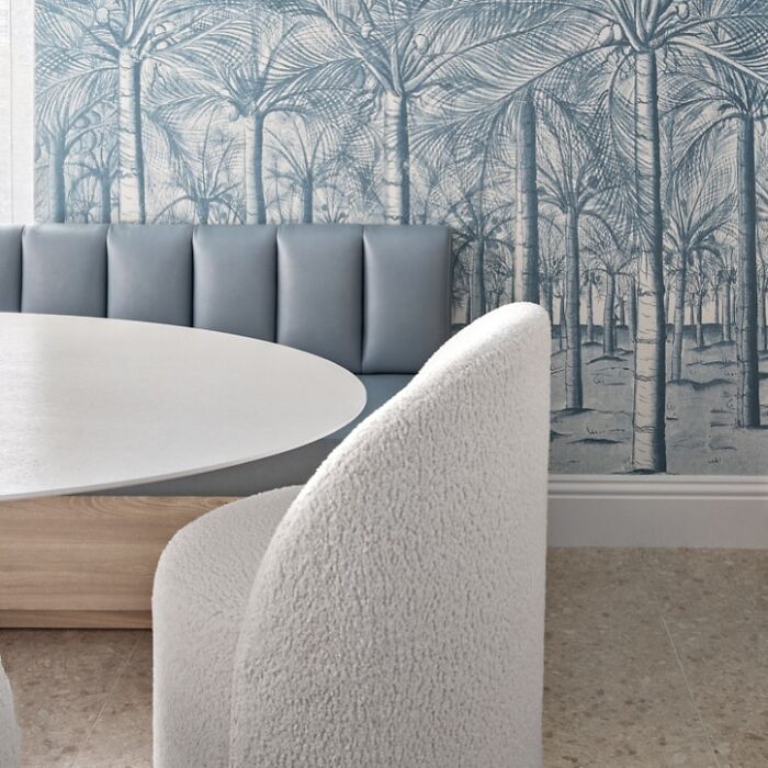 Dining area with blue cushioned bench and palm tree wallpaper design