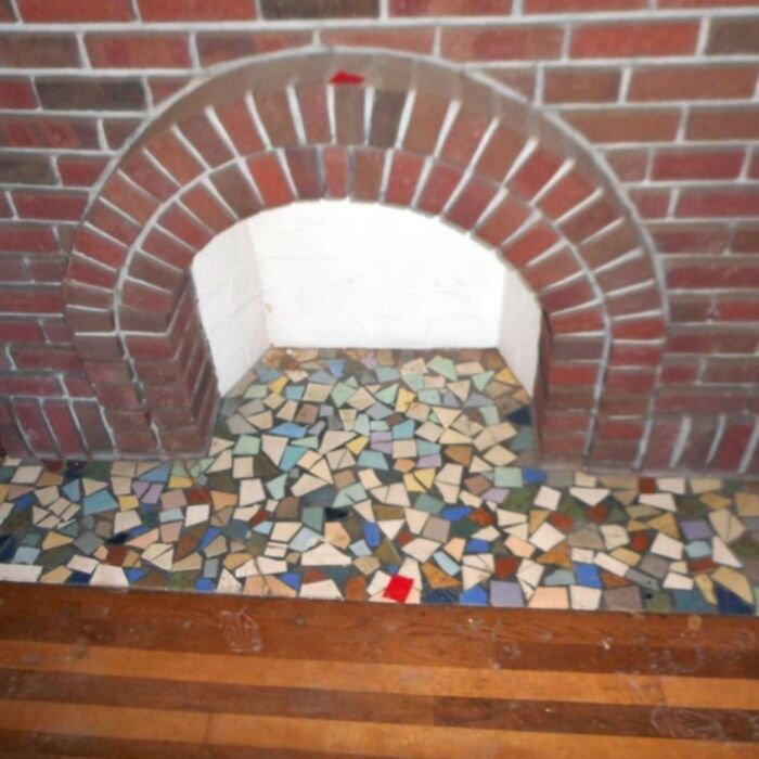 Colorful tile design fail under a small arched brick fireplace