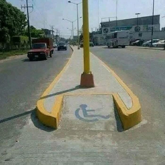 Road curb with handicap ramp blocked by a pole in a poor accessibility design fail