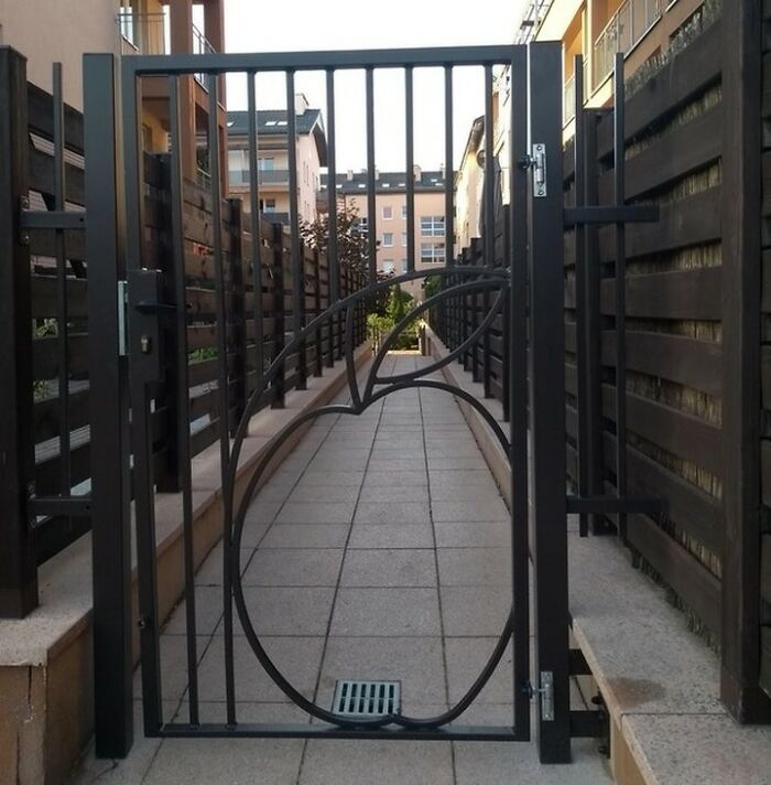 Metal gate with a fruit-shaped design blocking a pathway