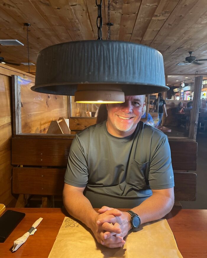 Man sitting under oversized hanging lamp that blocks his face