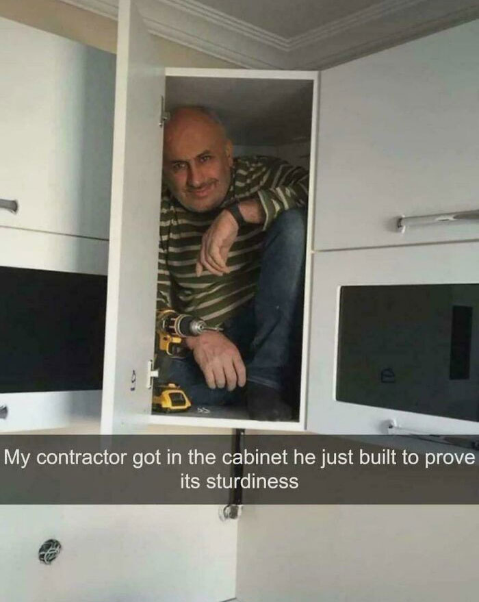 Contractor sitting inside newly built kitchen cabinet to prove sturdiness