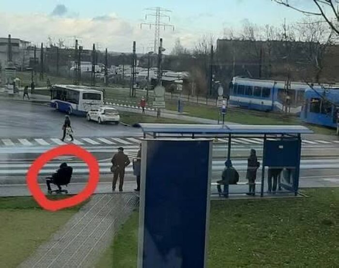 A person in a red circle sitting on an office chair at a bus stop, a prime example of Slavic Science.