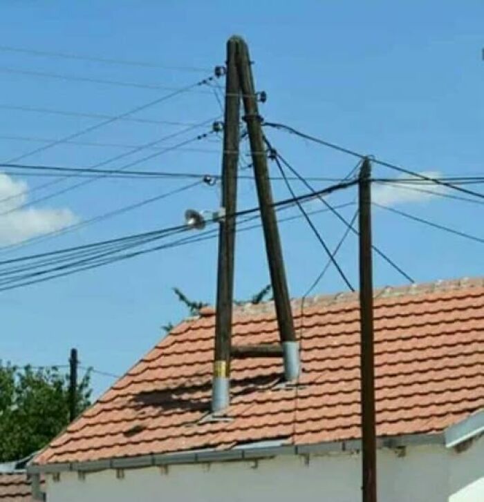 A creative electric pole construction showing unique Slavic science solutions above a house roof.