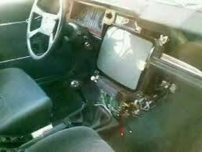An old CRT television fitted into a car's dashboard, displaying a unique approach to Slavic science and car modification.