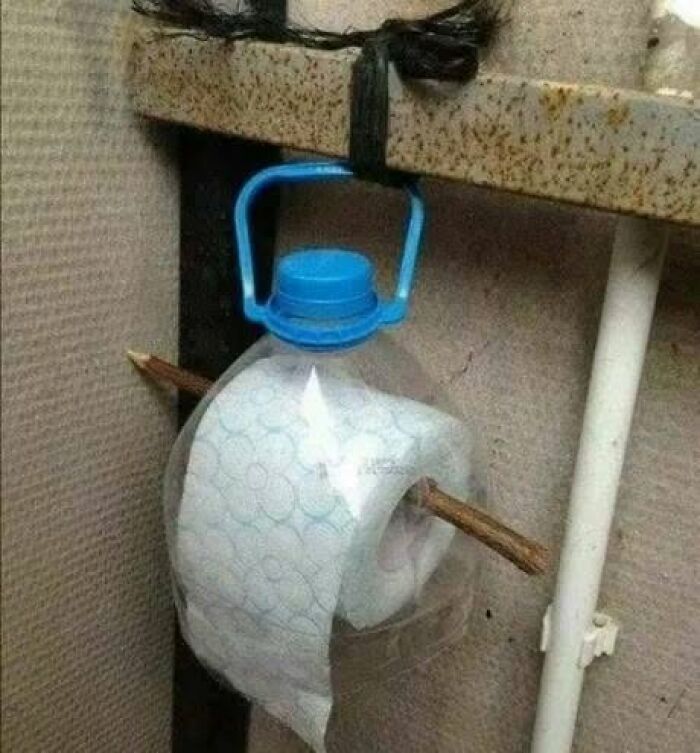 A toilet paper roll suspended by a stick through a plastic bottle handle, demonstrating clever Slavic science.