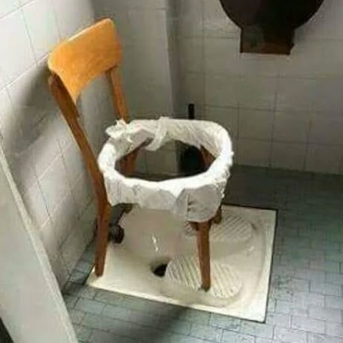 A wooden chair with a plastic bag as a seat, placed over a squat toilet, demonstrating Slavic science.