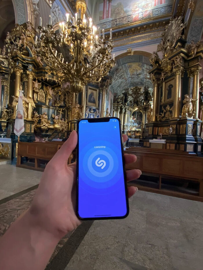 A person holding a phone with Shazam open, capturing audio in a richly decorated church, a great photo.